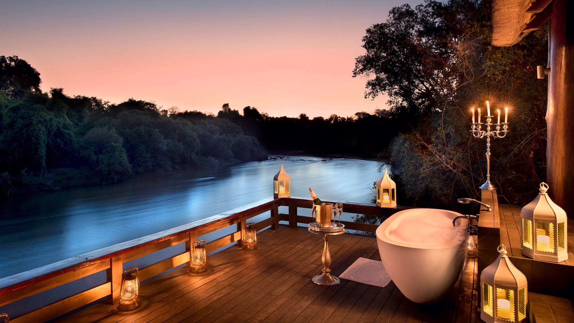 Deck with a freestanding bath overlooking the river at sunset