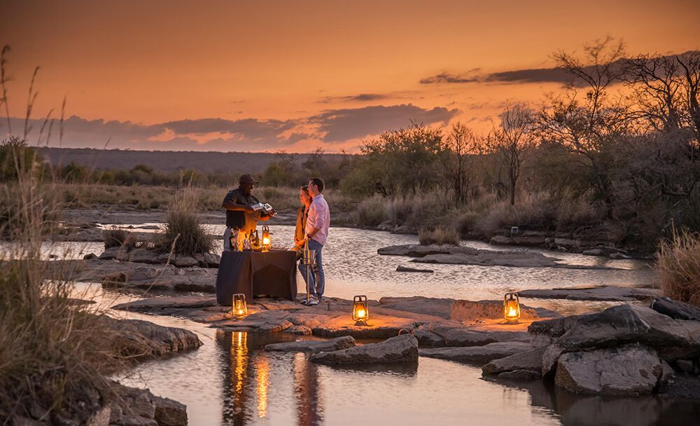 Guide serves couple a sunset drink in the river at Stanley and Livingstone Hotel in Victoria Falls Zimbabwe