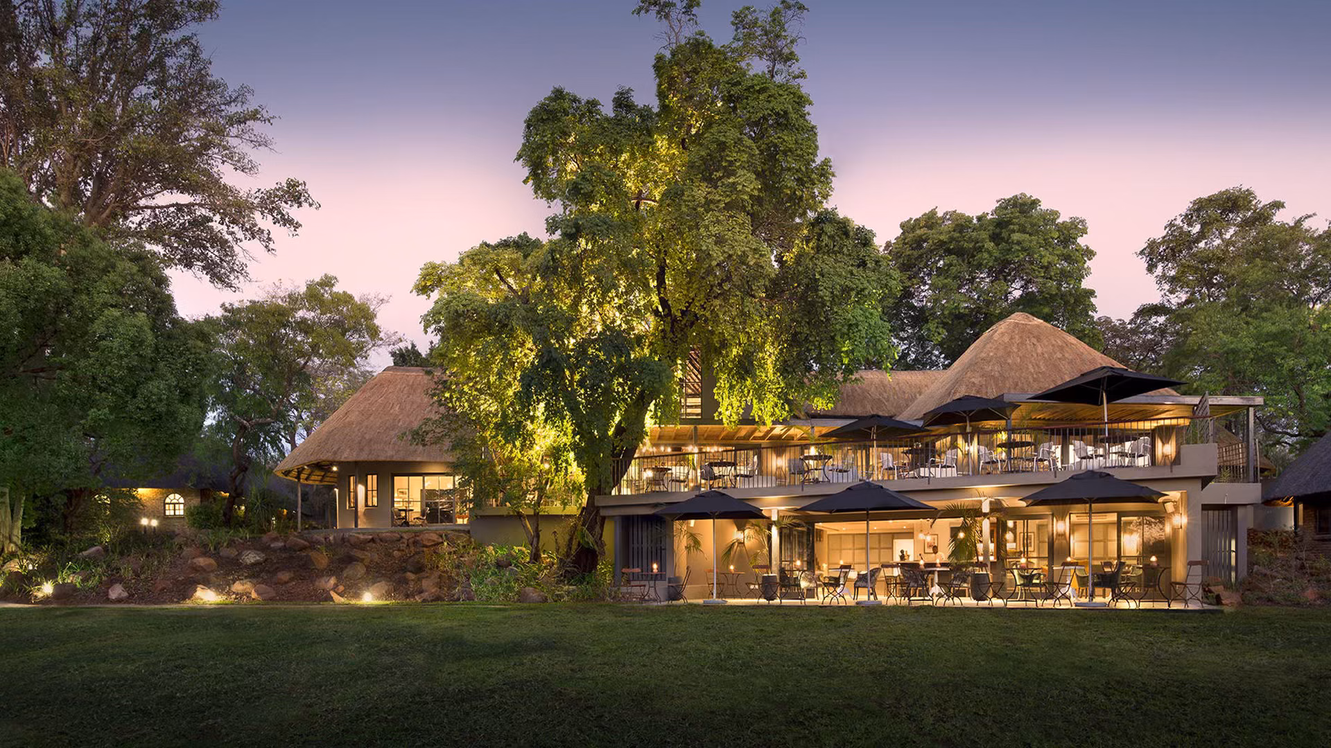 View of Stanley and Livingstone boutique hotel from their gardens at dusk, in Victoria Falls Zimbabwe