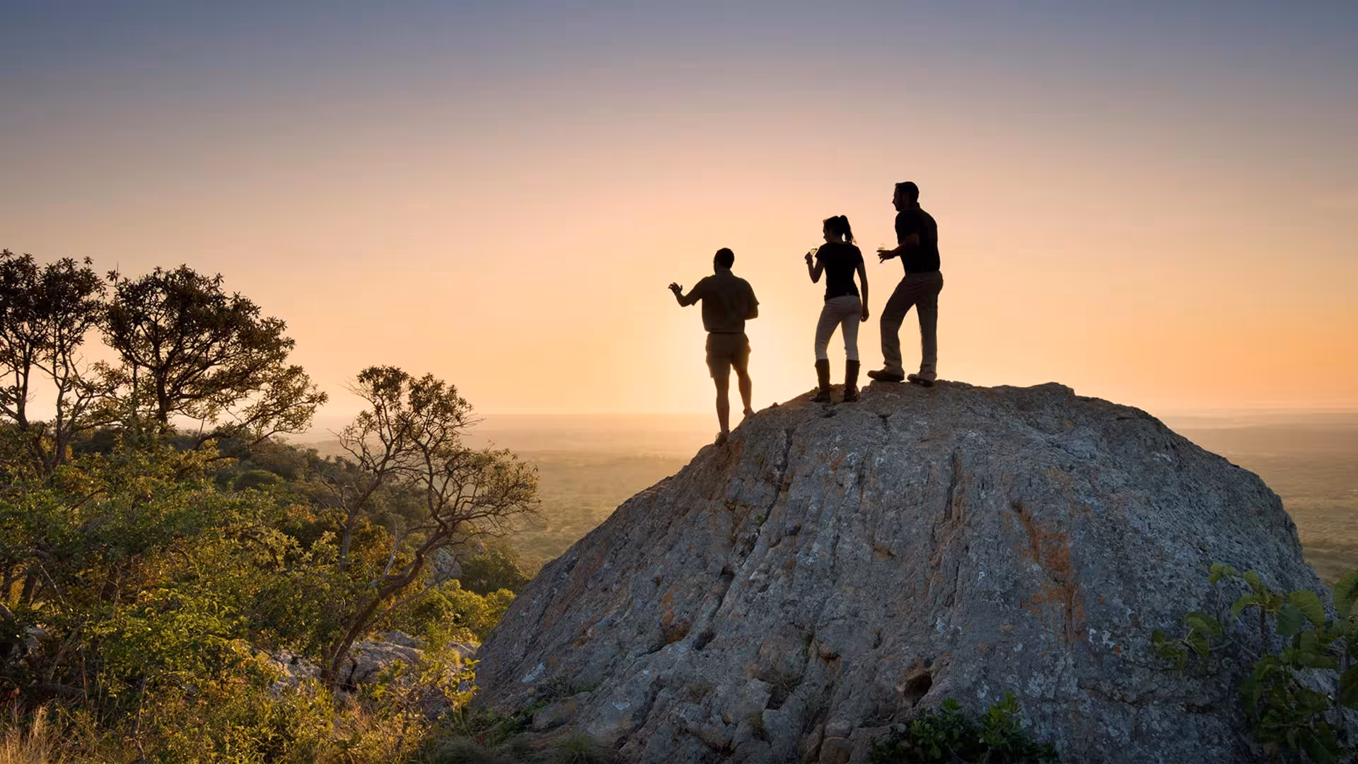 Guests silhouetted on a rock at sunset in Tanzania