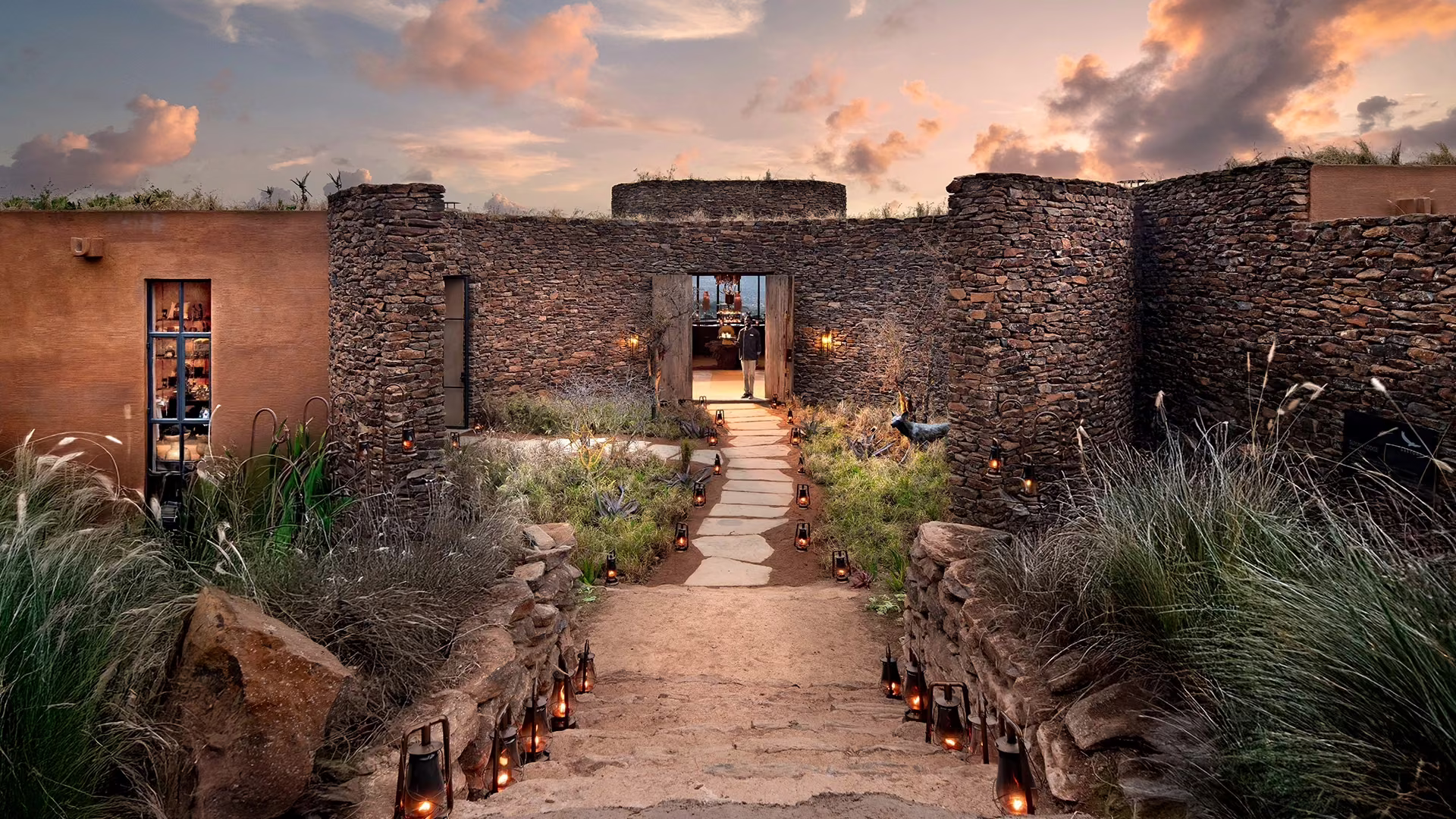Lantern-lit path leading through stone walls at Suyian Lodge at dusk