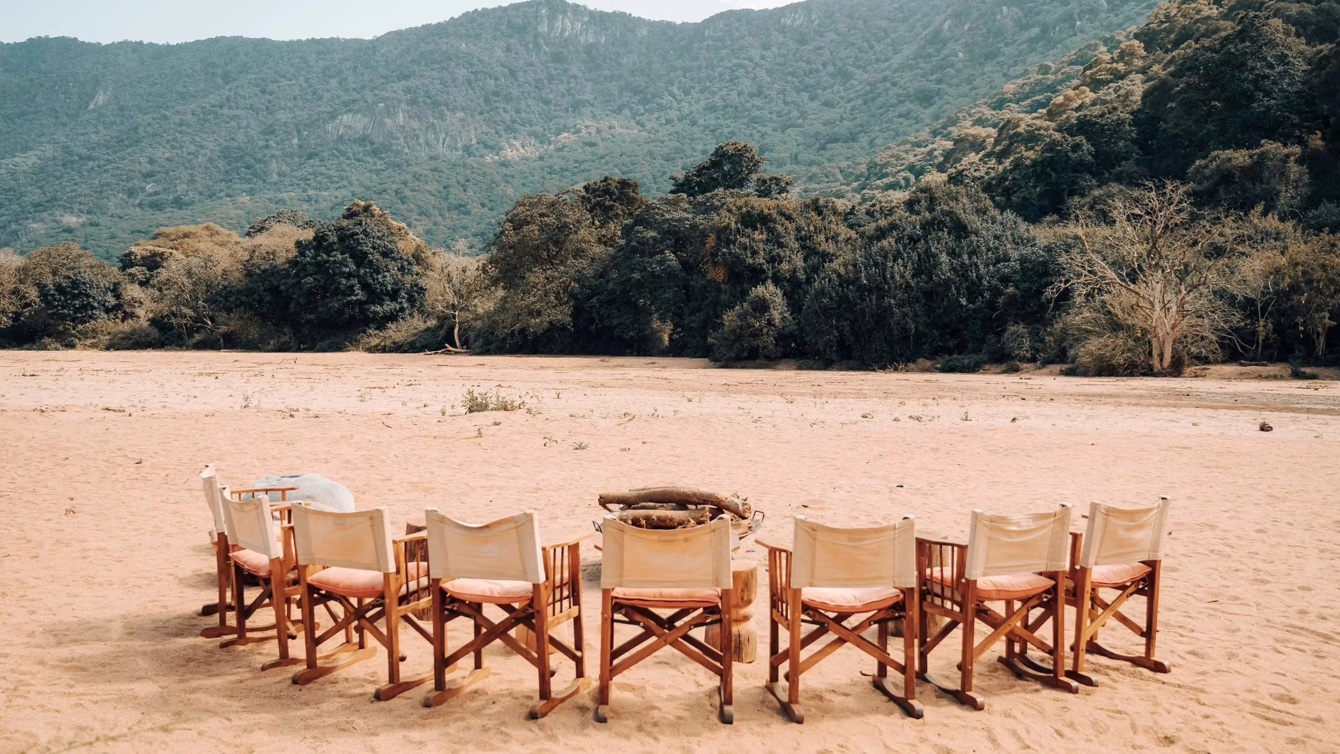 Outdoor table and chairs set up with hills behind at Wayo Manyara Green Camp